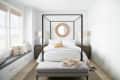 Canopy bed in a bright bedroom with a round mirror, two lamps, and a bench at the foot of the bed.