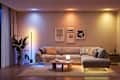 Cozy living room with a gray sectional sofa, colorful wall art, a round coffee table, and ambient lighting.