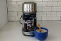 Espresso machine on a counter with a blue mug filled with coffee, against a tiled backsplash.