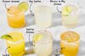 Six margarita cocktails in textured glasses, garnished with lime slices and salt rims, arranged on a light surface.