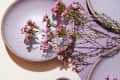 Speckled lavender ceramic dishes with pink flowers on a purple surface.