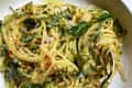 Spaghetti with creamy zucchini sauce, garnished with fresh basil and red pepper flakes in a white bowl.