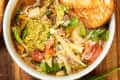 Minestrone soup in bowl with bread on the side.