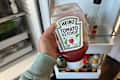 Someone holding bottle of ketchup.