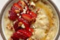 Custard oatmeal in bowl, topped with fruits and nuts.