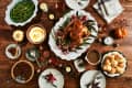 Thanksgiving dinner table with roasted turkey, green beans, mashed potatoes, pecan pie, and dinner rolls.