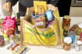 angled shot of an assortment of trader joe's groceries in a yellow and tan trader joe's tote bag - and some of the groceries are scattered around the bag on the counter.