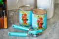 Two cans of Bianco DiNapoli crushed tomatoes on a marble counter with a turquoise can opener.