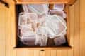 Open kitchen drawer filled with various sizes of clear plastic food storage containers.