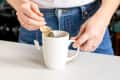 Someone dipping tea bag into tea mug.