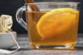 A Tea Hot Toddy in a clear glass mug with a cinnamon stick and a lemon slice.