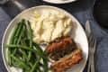 meatloaf on a plate with mashed potatoes and green beans