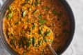 Ladling some lentil soup out of a dutch oven