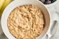peanut butter oatmeal in a bowl with fruit and honey near it