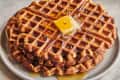 sweet potato waffles being drizzled with maple syrup