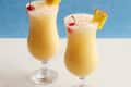 two painkiller cocktails with fruit on marble with a blue marble background
