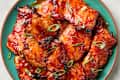 overhead shot of filipino barbecue chicken on s teal plate, topped with green onion