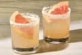 angled shot of two palomas in rocks glasses with salt on the rim and garnished with grapefruit