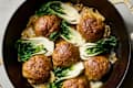 angled shot of lions head meatballs with bok choy in a bowl