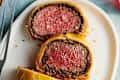 Overhead shot of beef Wellington on a platter, two slices cut crosswise and laid flat to show interior