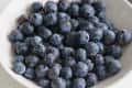 A close-up of fresh blueberries piled in a white bowl, showcasing their deep blue color and round shape.