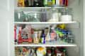 Organized pantry shelves with glass jars, mixing bowls, bread, snacks, and canned goods.