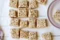 Rice Krispie treats cut into squares on parchment paper with a pink plate and a purple patterned napkin.