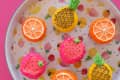 Image 6: Cupcakes decorated as fruits on a colorful fruit-patterned tray.