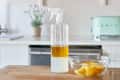 Spray bottle with yellow liquid and bowl of lemon wedges on kitchen counter.