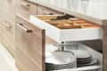 A photo shows an opened kitchen cabinet and drawer, filled with small and big plates, from Ikea