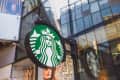 Starbucks logo on a circular sign outside a modern glass building.