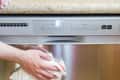 Person cleaning stainless steel dishwasher with a cloth.