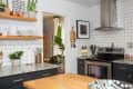 Modern kitchen with black cabinets, open shelves, white subway tiles, and stainless steel appliances.