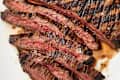 Steak with grill marks, partially sliced, on a platter