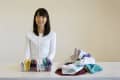 Woman in white sweater organizing colorful folded clothes on a table.