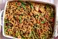 Baked green bean casserole topped with crispy fried onions in a white dish.