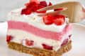 A slice of strawberry delight on a plate seen from the side with a fork cutting into it.