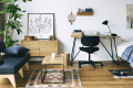 Modern bedroom with wooden furniture, black chair, desk, plant, and wall art.