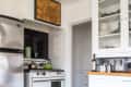 Retro kitchen with green, black, and cream checkered floor, vintage stove, stainless steel fridge, and white cabinets.