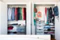 Open closet with organized clothes, shoes, and accessories, featuring colorful shirts, dresses, and a small orange mirror.