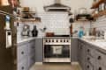 Modern kitchen with gray cabinets, stainless steel appliances, white subway tile backsplash, and various kitchen gadgets.