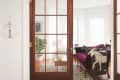 French doors open to a cozy living room with a purple sofa, decorative pillows, a horse blanket, and a potted plant.