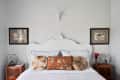 White ornate headboard with decorative pillows, framed art, and geometric decor on bedside tables.