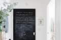 A large door is painted with black chalkboard paint and has white chalk markings on it.