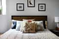 Bed with geometric patterned bedding, decorative pillows, wooden headboard, and framed art on the wall.