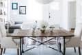 Dining room with wooden table, clear chairs, beige armchairs, and white hydrangeas in vases.