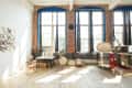Loft studio with brick walls, large windows, ceramic plates on wall, and pottery equipment.