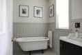 Clawfoot bathtub in a bathroom with beadboard walls, framed photos, and a towel on a rack.