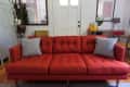 Red mid-century modern sofa with two gray patterned pillows in a living room with lockers and a console table.