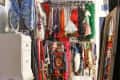 Eclectic closet with colorful clothes, vintage chandelier, white bench, and cowhide rug on wooden floor.